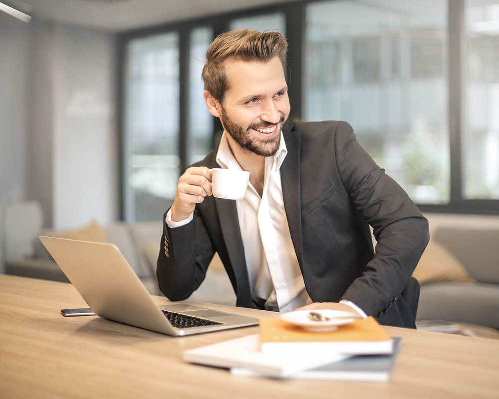 A professional stepping back from the screen with a cup of coffee