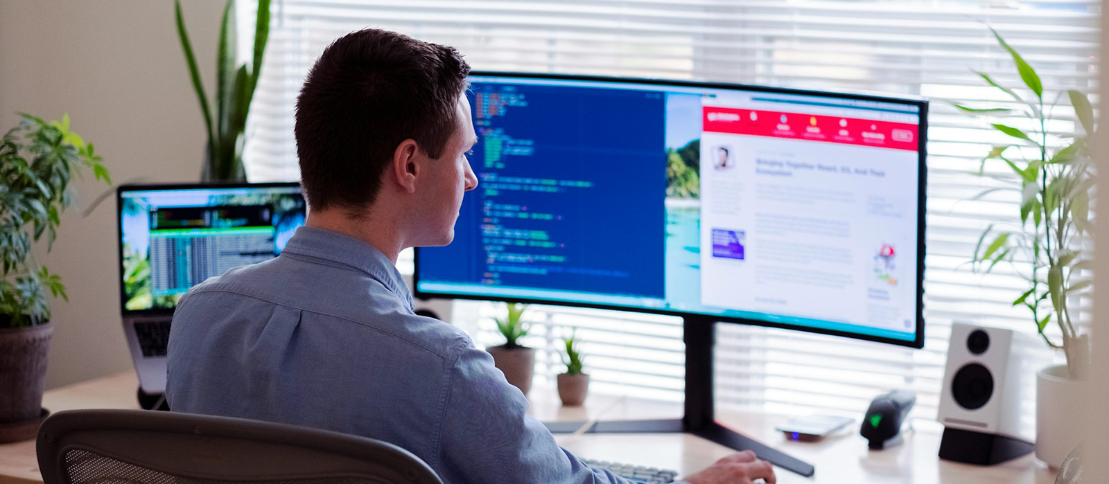 An IT professional working at a two-monitor desk in daylight