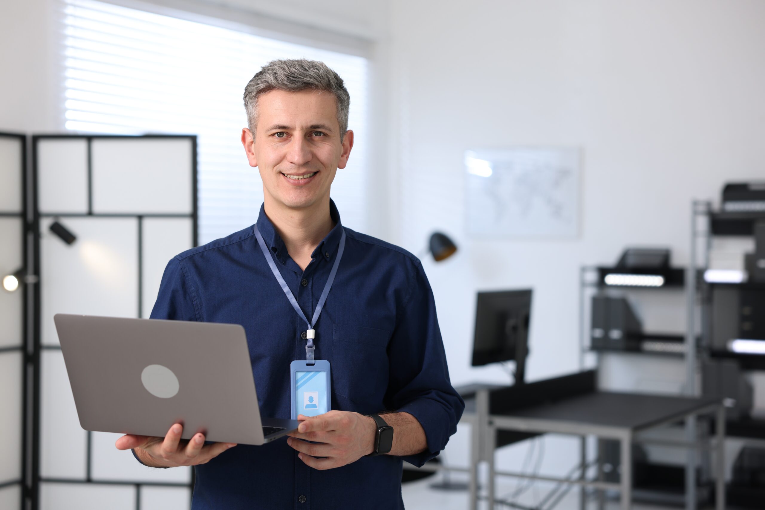Portrait of smiling engineer with laptop in office. Space for text